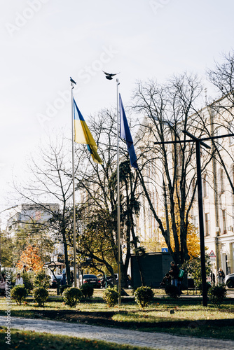 The flag of the European Union and Ukraine are hanging outside on a flagpole in the wind, swaying in the wind.