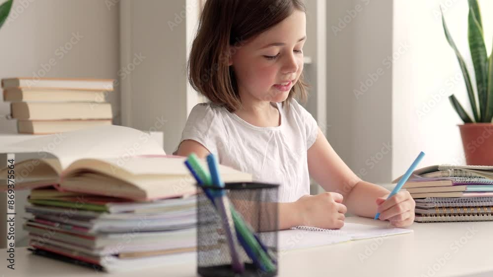 Child doing her homework art a desk. School girl whrites in a notebook. Child doing her homework art a desk. School girl whrites in a notebook.