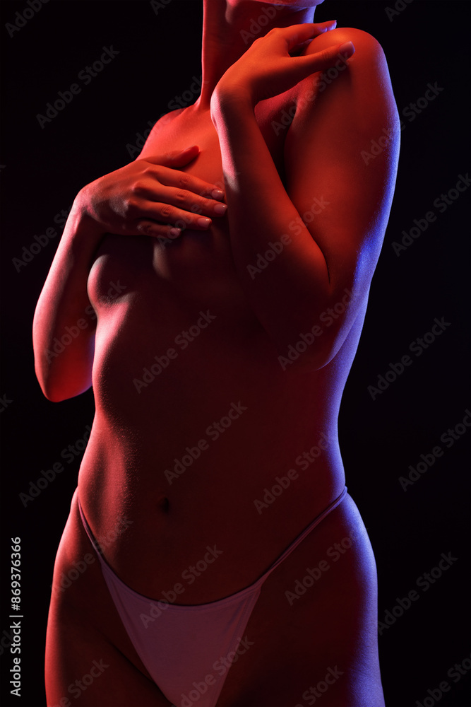 Naklejka premium Slim sexy woman in lingerie on a dark background. Her body is illuminated with blue and red lights.