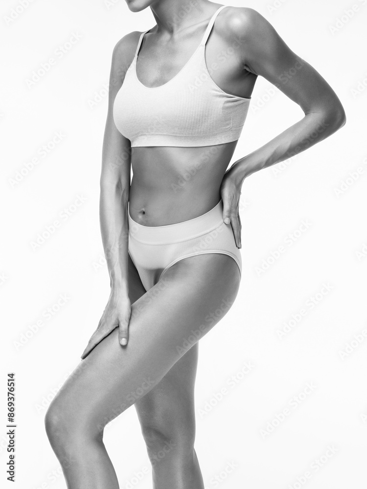 Fototapeta premium A slender swarthy woman in beige underwear on a white background. Healthy lifestyle, sport and diet.