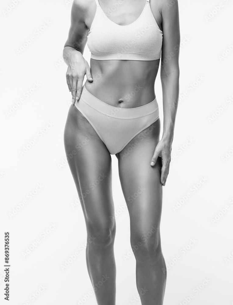 Fototapeta premium A slender swarthy woman in beige underwear on a white background. Healthy lifestyle, sport and diet.