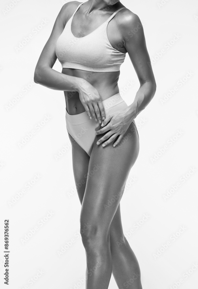 Naklejka premium A slender swarthy woman in beige underwear on a white background. Healthy lifestyle, sport and diet.
