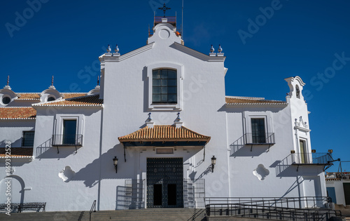 Bathed in the Andalusian sun, the Hermitage of El Rocío stands with its striking white facade and terracotta roofs, a testament to traditional Spanish religious architecture in Huelva.