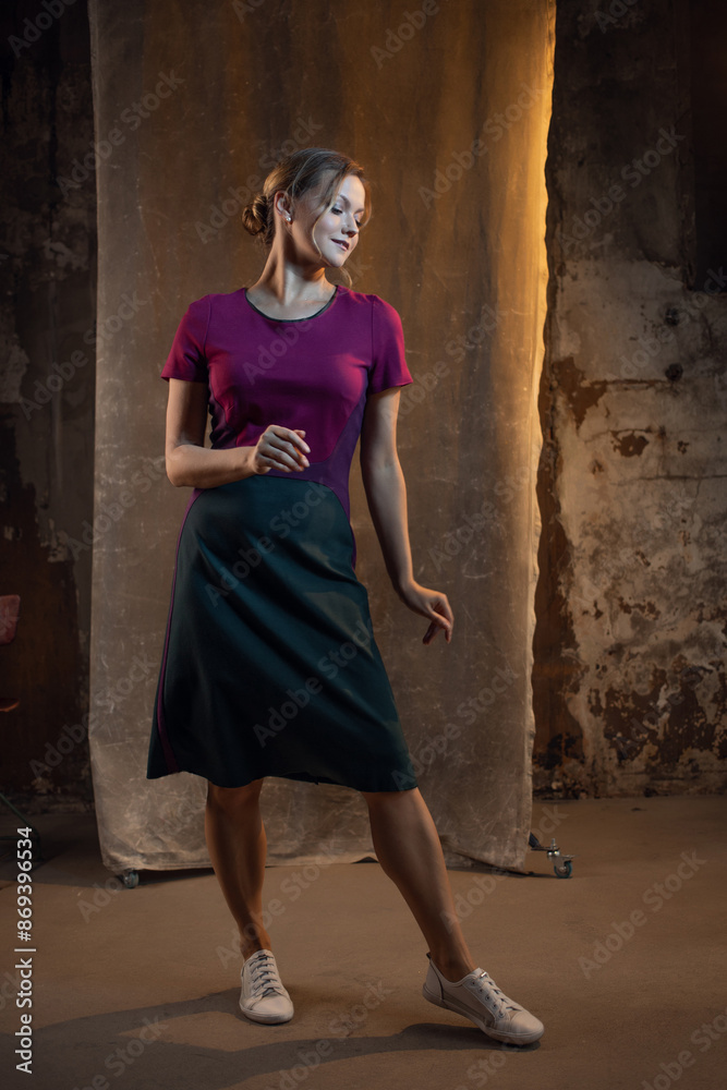 Fototapeta premium Elegant blonde in a medium-length casual dress. photo in dark colors