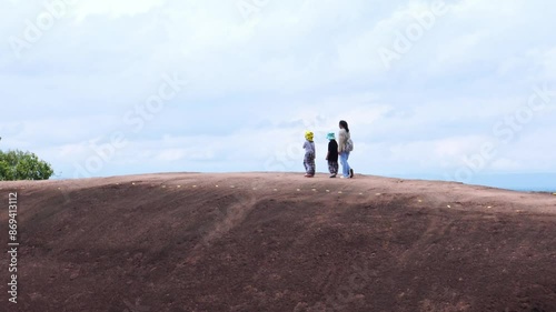 Adventurers stand on a large boulder in the middle of a forest in a national park, Three Whale Rock or Hin Sam Whales in Buegkan province, Thailand.