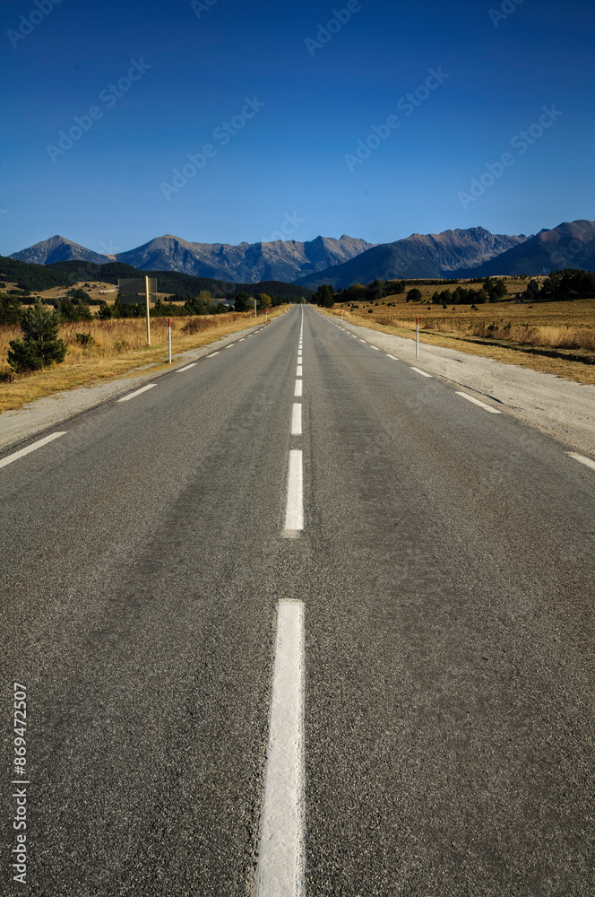 Naklejka premium Straight road from La Quillane to Les Angles (France). At the background, some mountains from Pyrenees Orientales