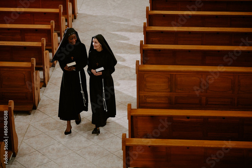 Tableau sur toile High angle view of two Caucasian and Black Catholic nuns holding prayer books, w