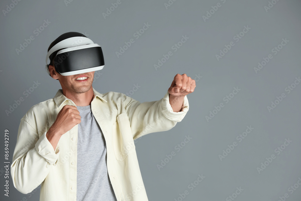 Smiling man using virtual reality headset on gray background, space for text Smiling man using virtual reality headset on gray background, space for text