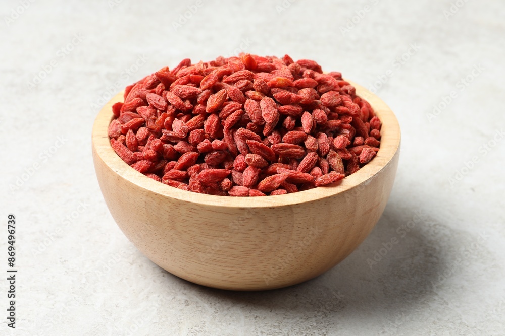 Dried goji berries in bowl on light textured table, closeup Dried goji berries in bowl on light textured table, closeup