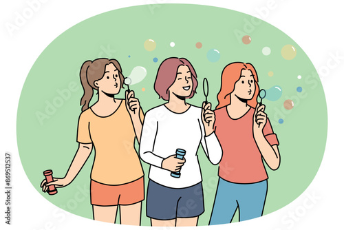 Teenage girls inflate soap bubbles enjoying outdoor recreation in hot summer weather. Three high school girls love to hang out and have fun playing in park, for concept of carefree childhood