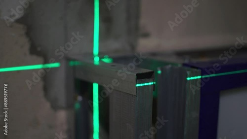 Laser building level with green beans is shines on the metal construction for marking a flat surface.