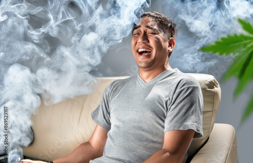 asian man laughing on sofa with smoking in relaxing time at home with weed photo