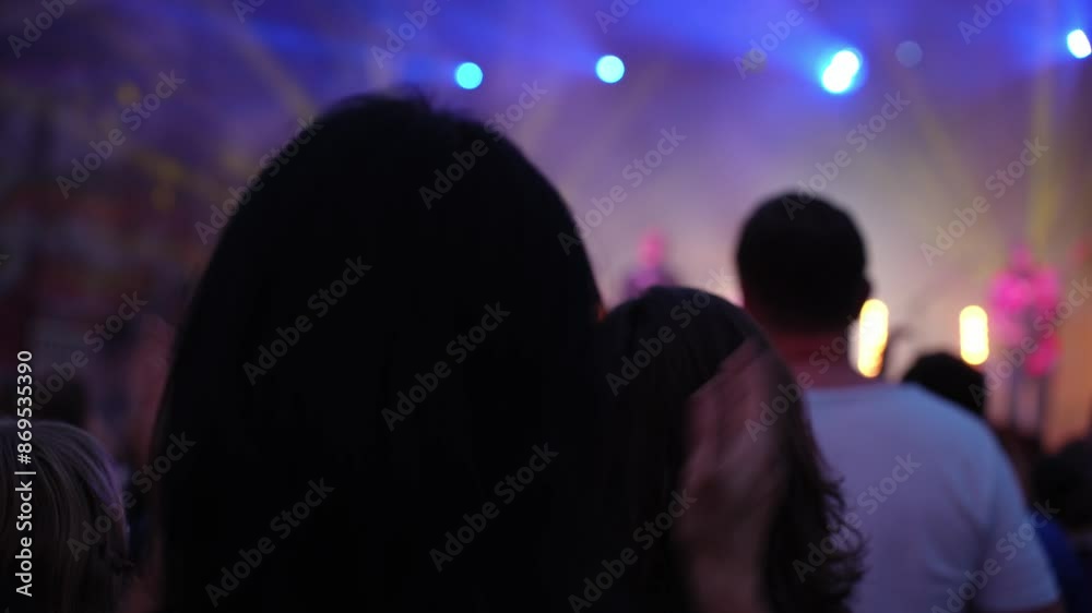 Silhouettes of crowd at concert in front of stage with bright spotlights. People enjoy live music at the band's performance. Concert hall with musicians on stage and fans during music festival Silhouettes of crowd at concert in front of stage with bright spotlights. People enjoy live music at the band's performance. Concert hall with musicians on stage and fans during music festival