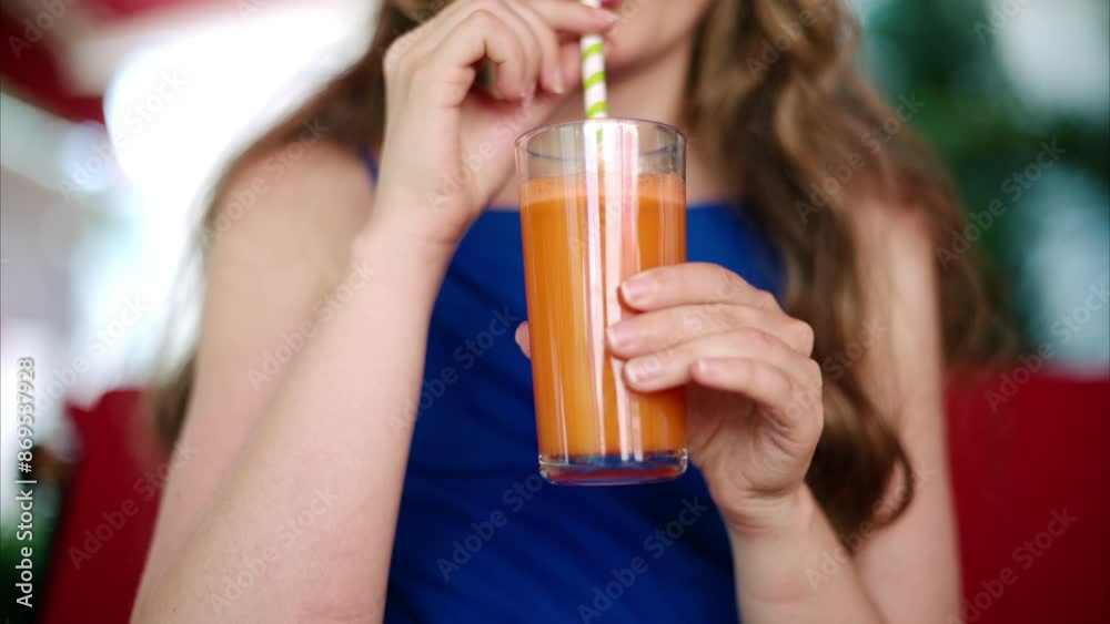 Woman in a blue dress drinking a carrot juice at a restaurant terrace