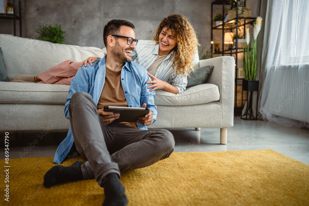 Obraz premium Boyfriend sit on the floor use tablet while girlfriend lie and hug him