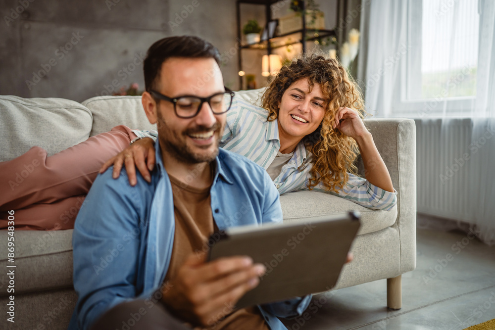 Boyfriend sit on the floor use tablet while girlfriend lie and hug him Boyfriend sit on the floor use tablet while girlfriend lie and hug him