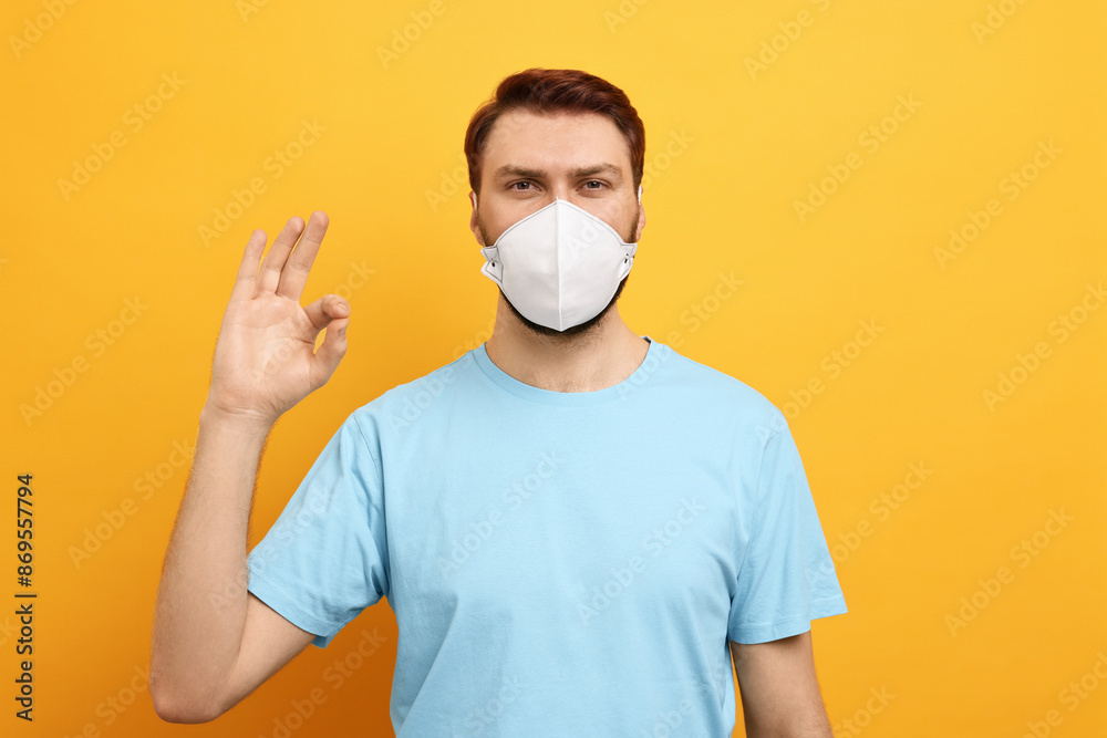 Man in respirator mask showing OK gesture on yellow background Man in respirator mask showing OK gesture on yellow background