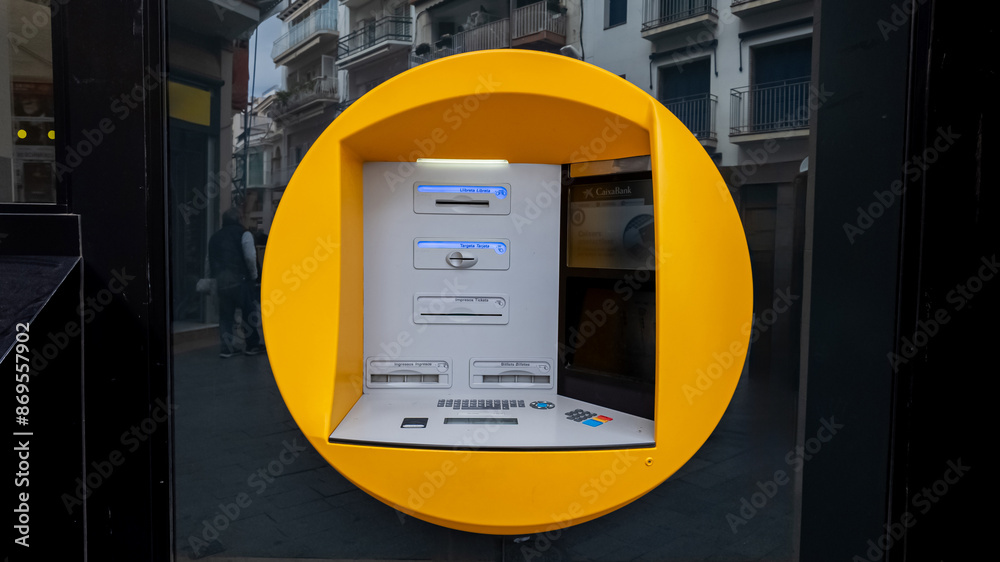 A modern ATM machine with a bold yellow frame on a city street in ...
