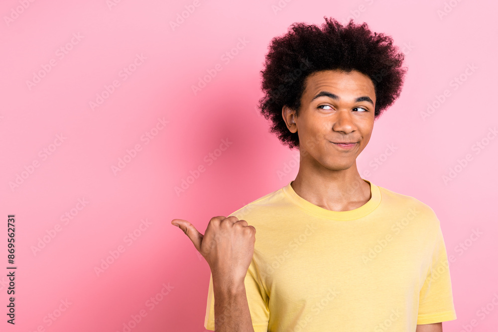Photo of doubtful unsure guy dressed yellow t-shirt looking showing thumb empty space isolated pink color background Photo of doubtful unsure guy dressed yellow t-shirt looking showing thumb empty space isolated pink color background