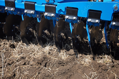 Close-up of a large modern plow blue color or disc harrow for cultivating the land. photo