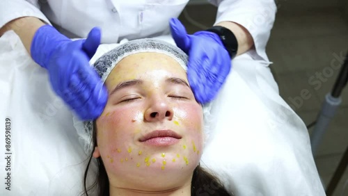 facial massage with a special solution called biorepeel, the procedure is in a beauty salon, the specialist wears blue gloves and the girl is very pleasantly surprised by the massage.