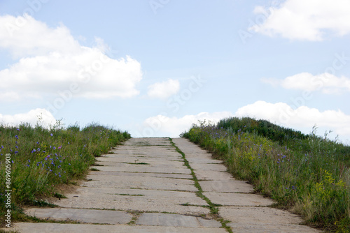 Stone path on the dunes with blue sky and clouds in the background