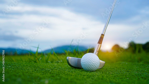 Golf ball and wooden driver on green grass background.