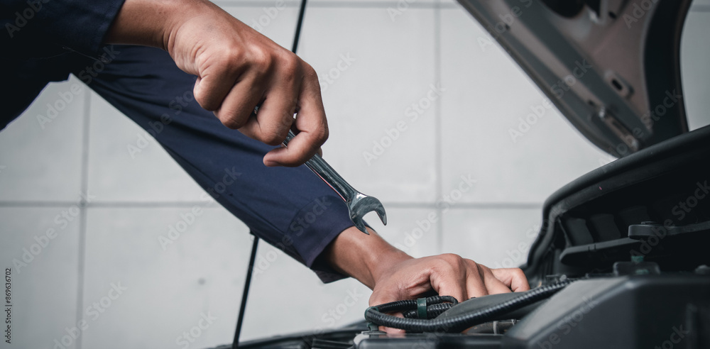 Mechanic using wrench while working on car engine outside the service center , Repair and service. Mechanic using wrench while working on car engine outside the service center , Repair and service.