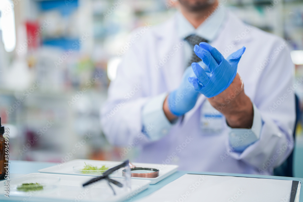 Scientists prepare for the experiment by wearing latex gloves. An experimenter arranges experimental equipment on a table with test tubes and chemicals for making drugs and biochemical for human. Scientists prepare for the experiment by wearing latex gloves. An experimenter arranges experimental equipment on a table with test tubes and chemicals for making drugs and biochemical for human.