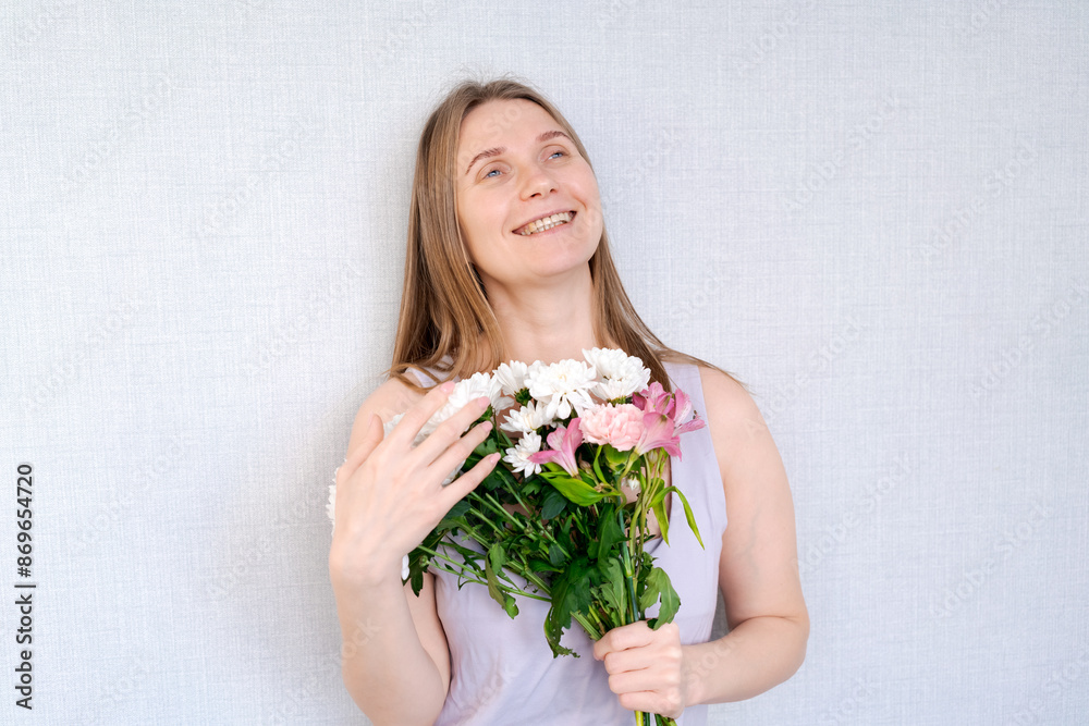 A woman is holding a bouquet of flowers and smiling A woman is holding a bouquet of flowers and smiling