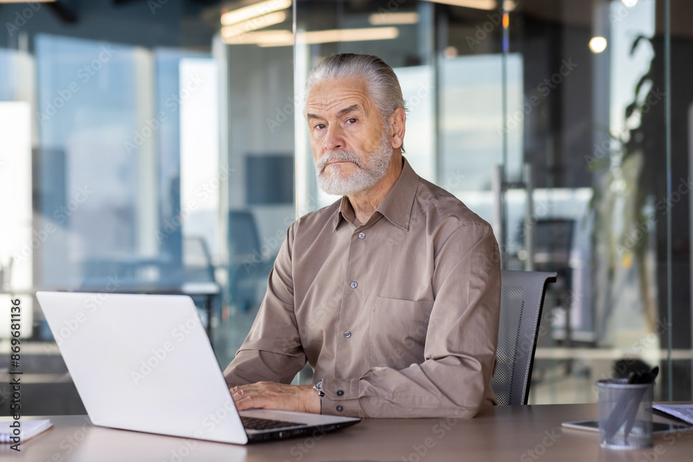 Portrait of an experienced senior business professional working on his laptop in a contemporary office environment. Thoughtful and focused, he embodies workplace productivity and dedication. Portrait of an experienced senior business professional working on his laptop in a contemporary office environment. Thoughtful and focused, he embodies workplace productivity and dedication.