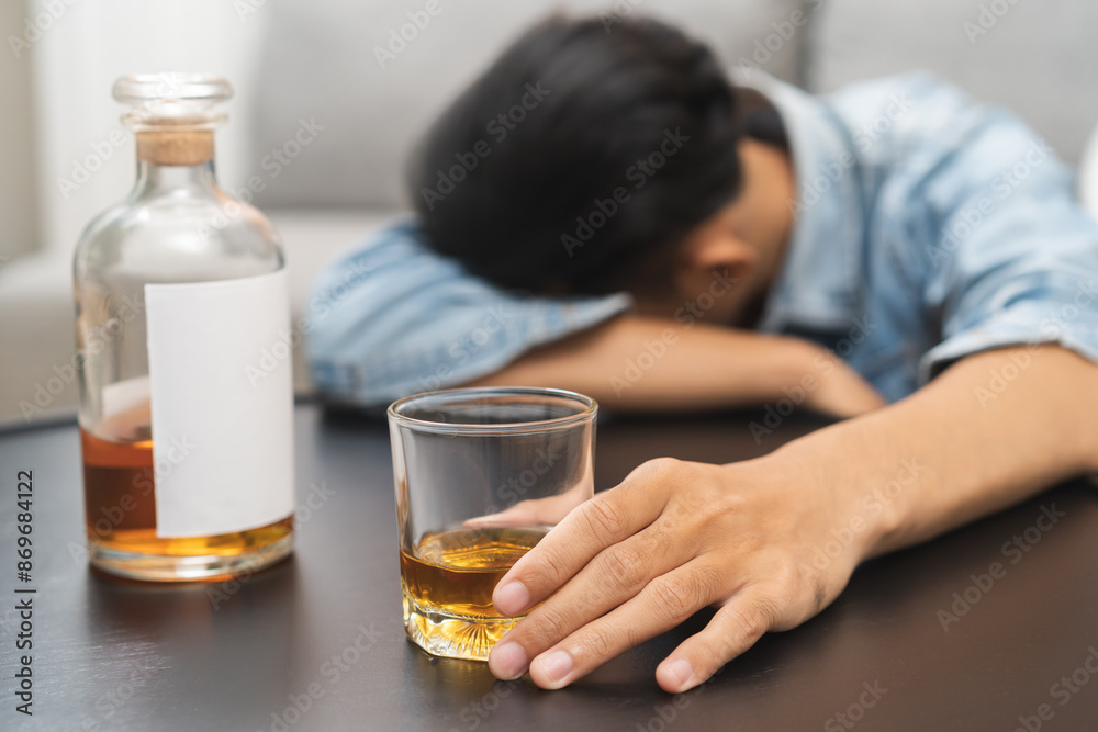 Health care alcoholism drunk, fatigue asian young man holding glass of whiskey, depressed male drink booze, sleep on table at home. Treatment of alcohol addiction, suffer abuse problem alcoholism. Health care alcoholism drunk, fatigue asian young man holding glass of whiskey, depressed male drink booze, sleep on table at home. Treatment of alcohol addiction, suffer abuse problem alcoholism.