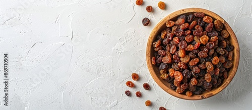 View from above of raisins in a rustic bowl on a blank white backdrop with space for text or other elements in the image. photo