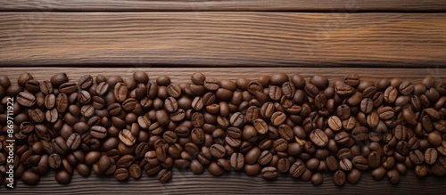 Coffee beans are arranged on a wooden surface background, creating a textured frame for a copy space image.