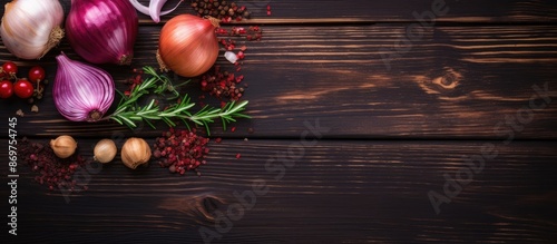 Red onion used as seasoning with chili pepper, rosemary, black pepper, and garlic on a dark wooden background in a top view setting with copy space image.