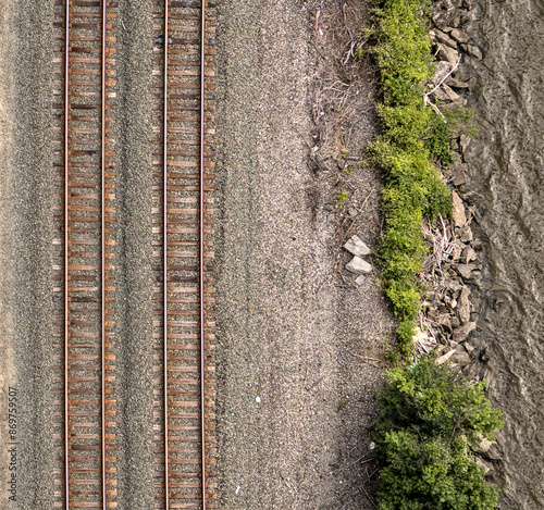 view of train tracks next to river from kingston rhinebeck bridge in hudson valley (railroad line near water near mountains) curve in track turning trains looking down new york state transport commute