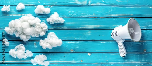 Blue wooden background with a blank cloud, a megaphone placed nearby, creating a top view copy space image for text demonstration. photo