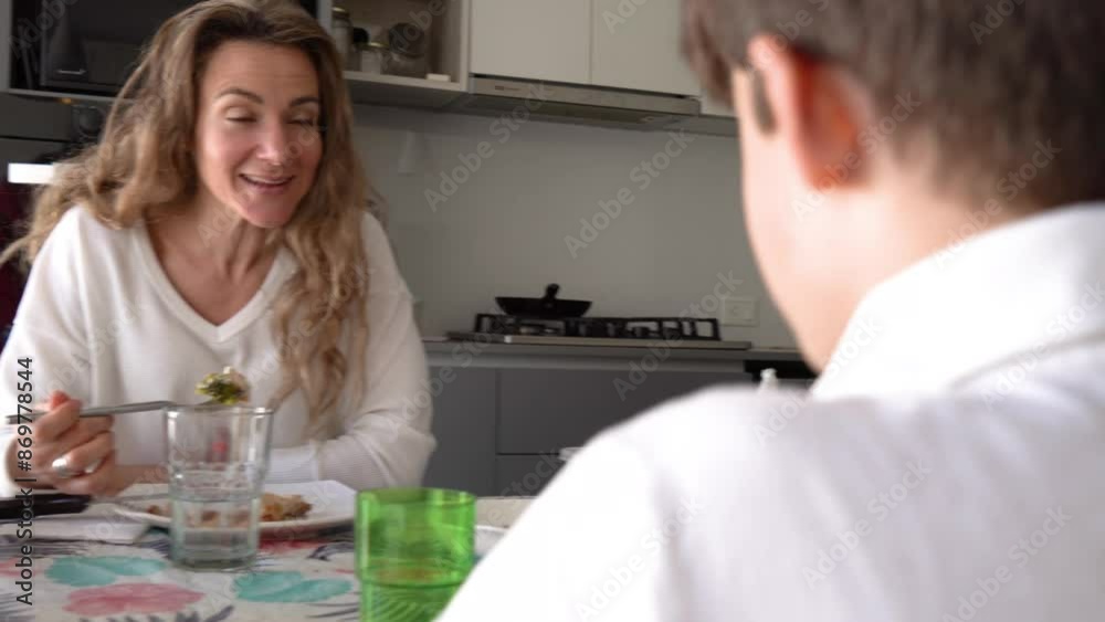 Smiling Mom Sharing a Meal with Her Son at the dining table. Smiling Mom Sharing a Meal with Her Son at the dining table.