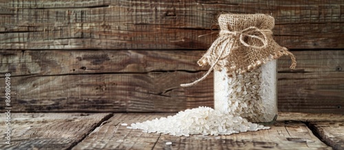 Rice grains displayed in a glass jar, set against a rustic wooden backdrop with ample white space for text or images--a versatile copy space image. photo