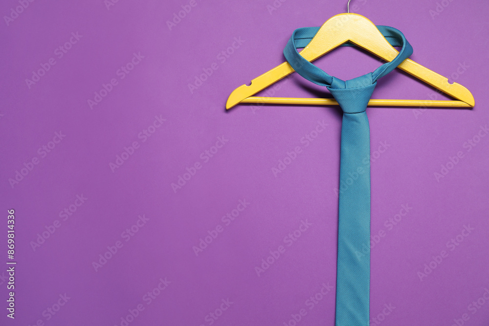 Hanger with necktie on purple background. Space for text Hanger with necktie on purple background. Space for text