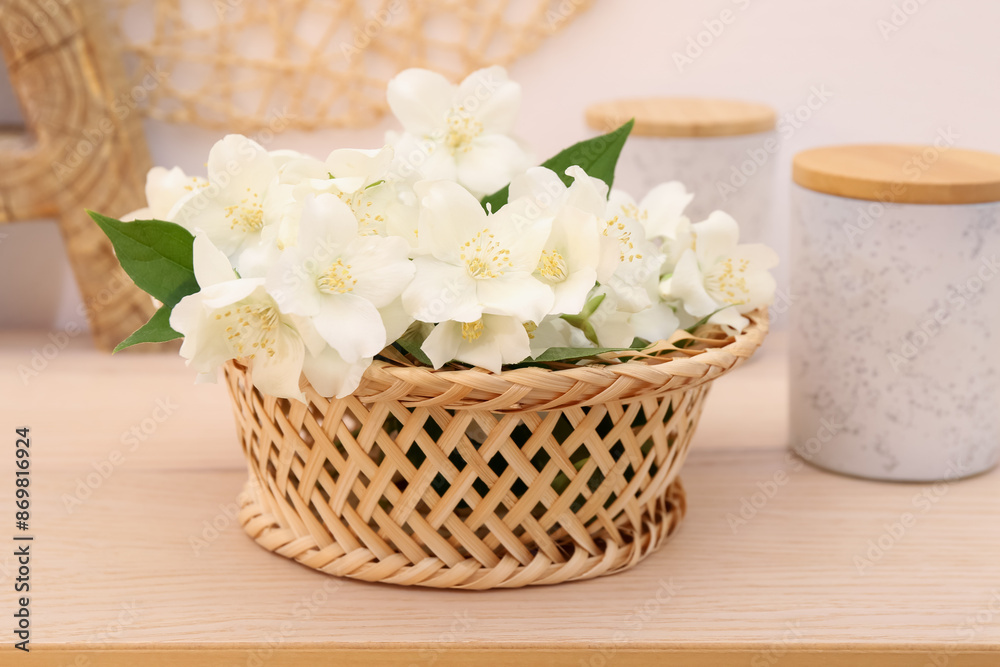 Beautiful jasmine flowers in wicker basket on wooden table