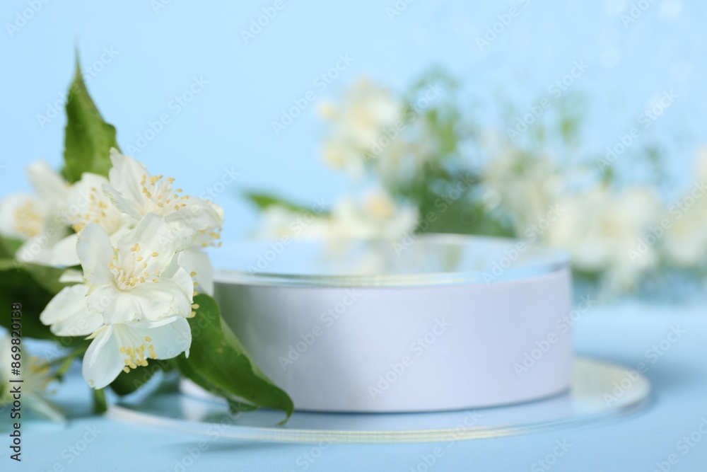 Presentation of product. White podium and beautiful jasmine flowers on light blue background closeup Presentation of product. White podium and beautiful jasmine flowers on light blue background closeup