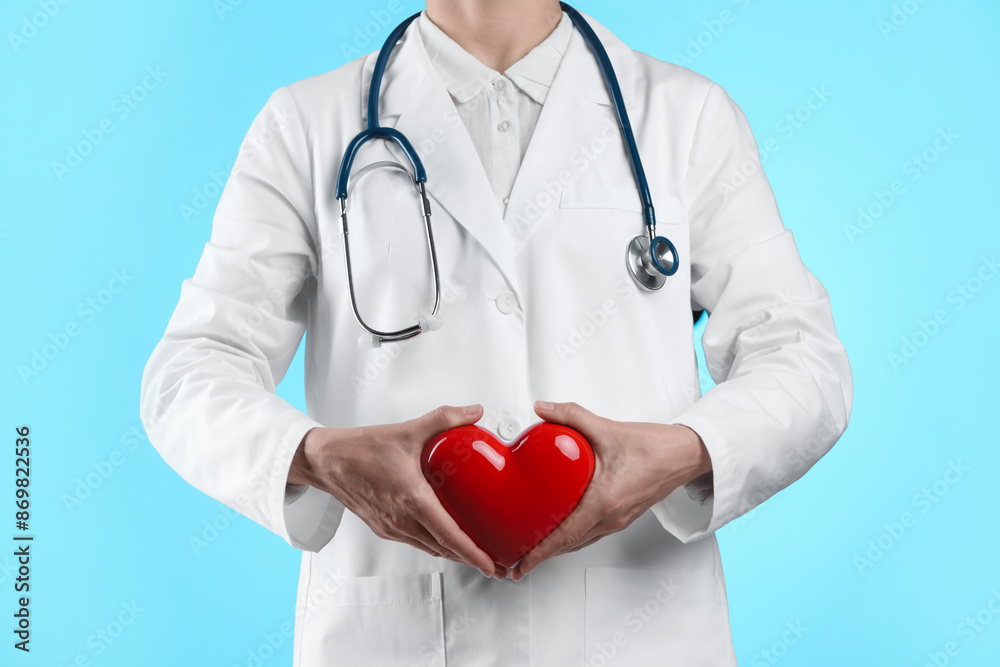 Doctor with red heart on light blue background, closeup Doctor with red heart on light blue background, closeup