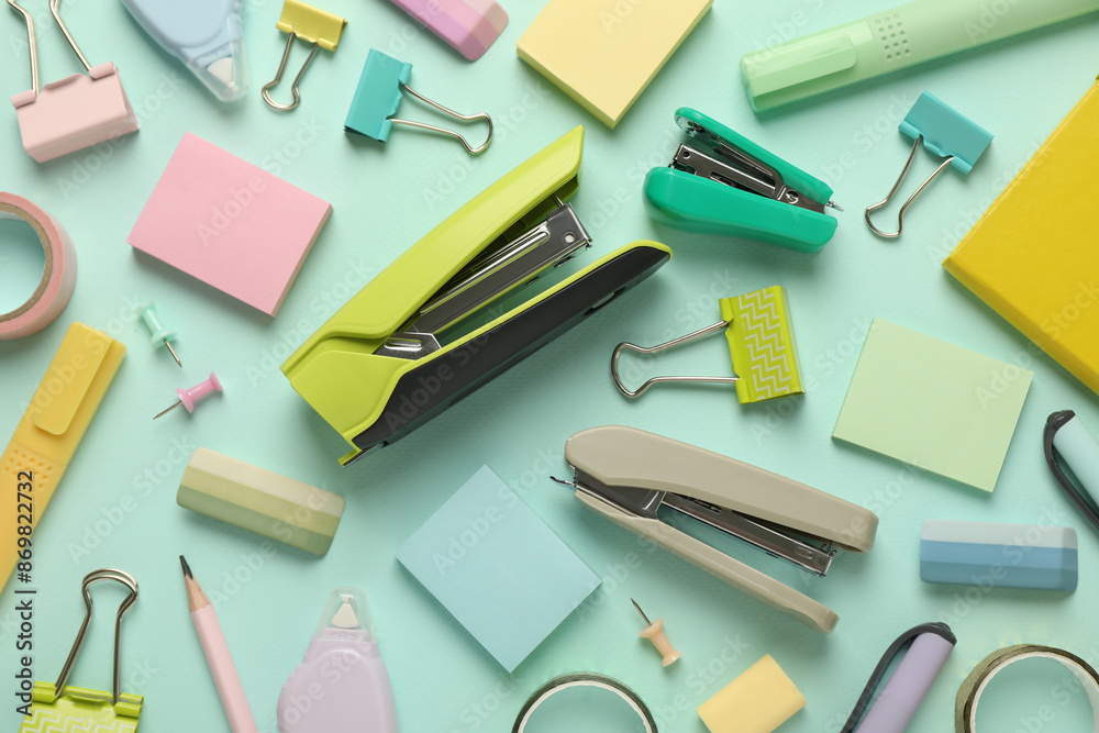 Flat lay composition with notebook, staplers and different stationery on turquoise background Flat lay composition with notebook, staplers and different stationery on turquoise background