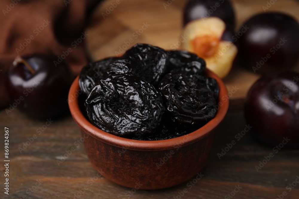 Tasty dried plums (prunes) in bowl on wooden table, closeup Tasty dried plums (prunes) in bowl on wooden table, closeup