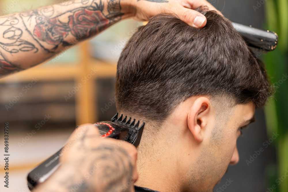 tattooed barber cutting the hair and beard of a young, dark-haired client.
tattooed barber cutting the hair and beard of a young, dark-haired client.