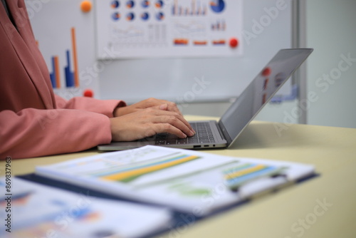 Young happy professional business woman employee sitting at desk working on laptop in modern corporate office interior. Smiling female worker using computer technology typing browsing web.