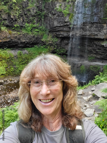 Solo traveller takes a selfie during her adventure. She is wearing a t-shirt and enjoying the remote location. Henrhyd is the highest waterfall in South Wales. photo