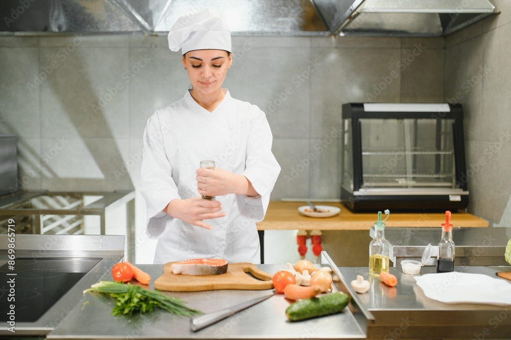 young beautiful female chef cooks salmon in restaurant kitchen young beautiful female chef cooks salmon in restaurant kitchen
