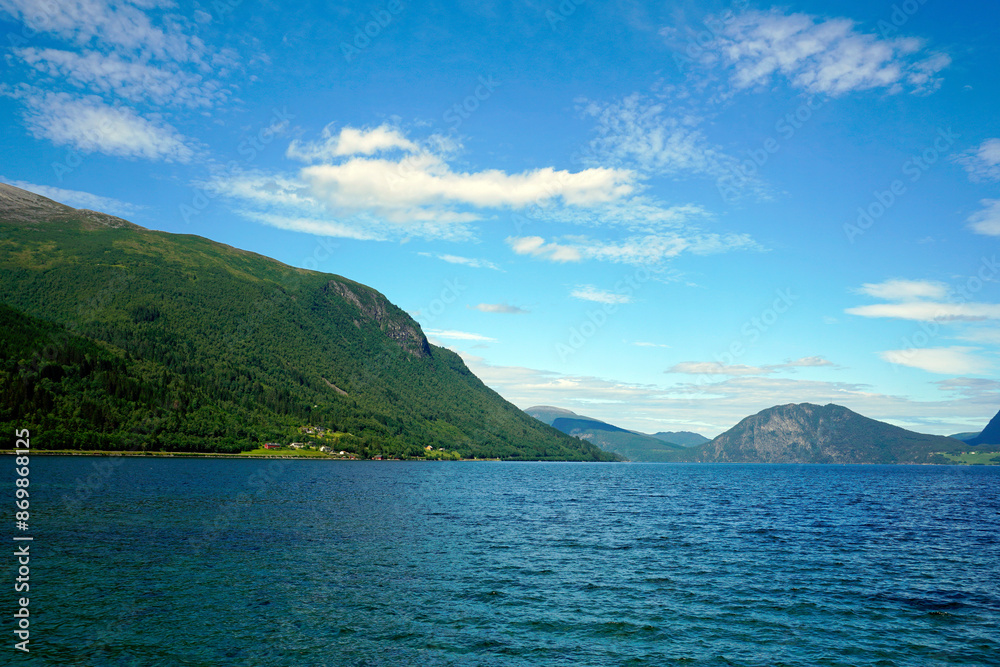Summer in the fjords of Norway. Mountain peaks Sky and white clouds.